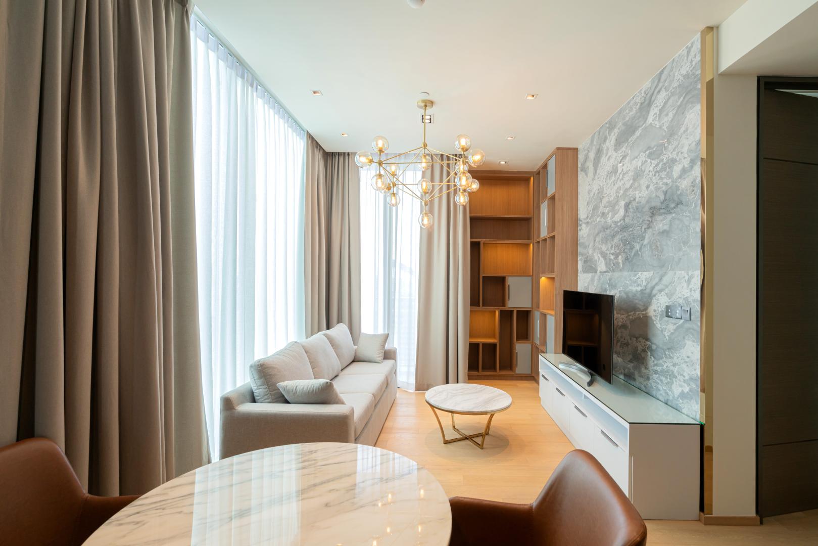A modern living room, featuring sheer curtains and heavy drapes.