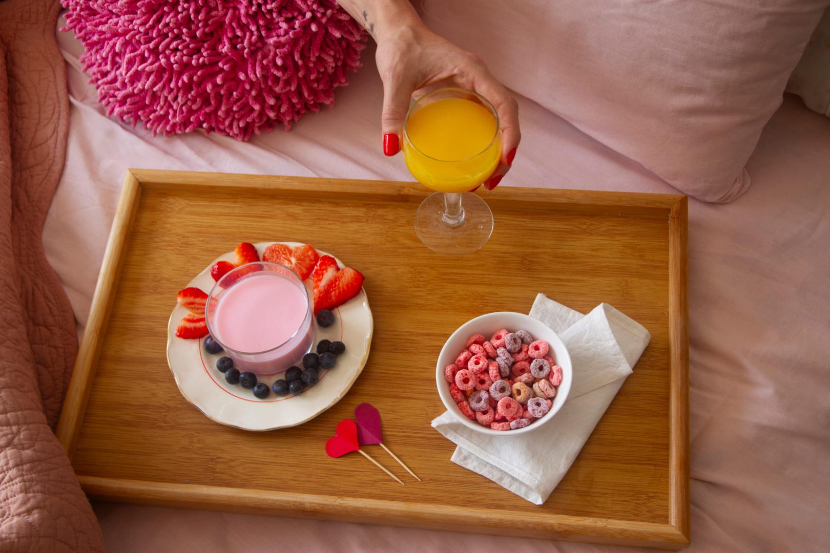 A romantic breakfast served in bed with pink bedsheets.