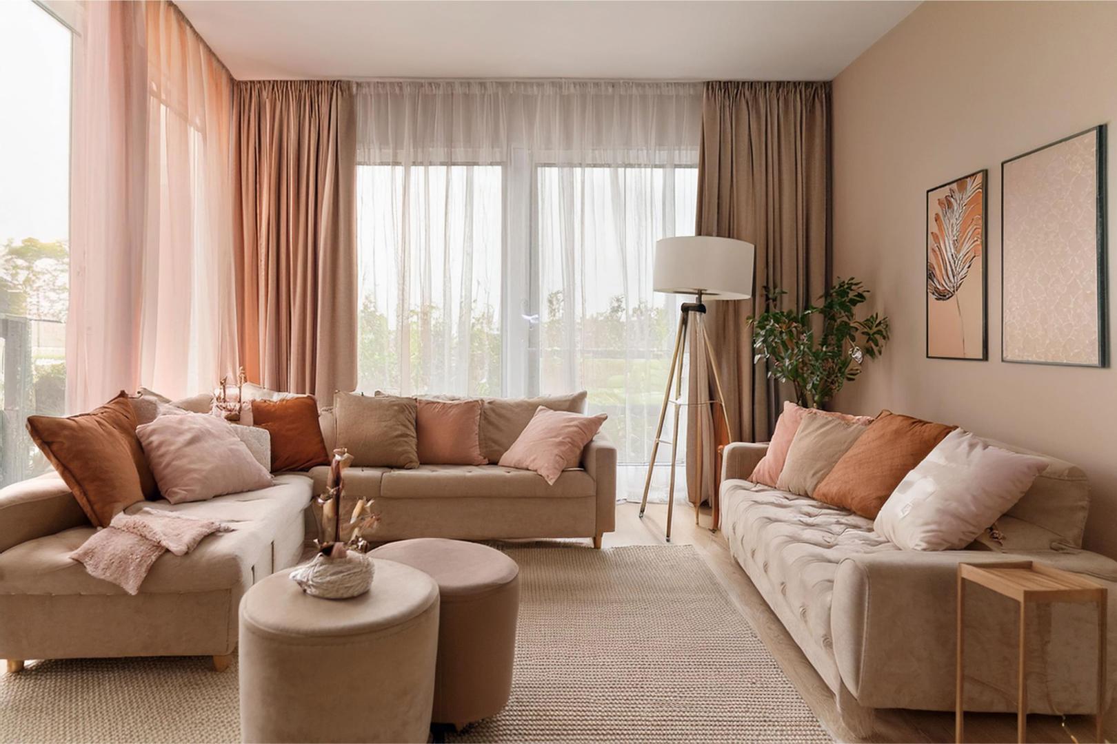 A living room in pink tones, featuring blackout curtains layered with sheer curtains.