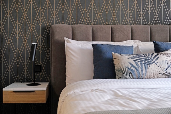 A modern bed with a gray chenille headboard.