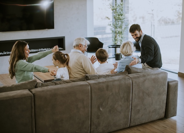 A family hanging out on a gray chenille couch.