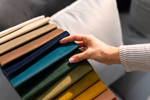 A woman's hand looking through chenille fabric samples.