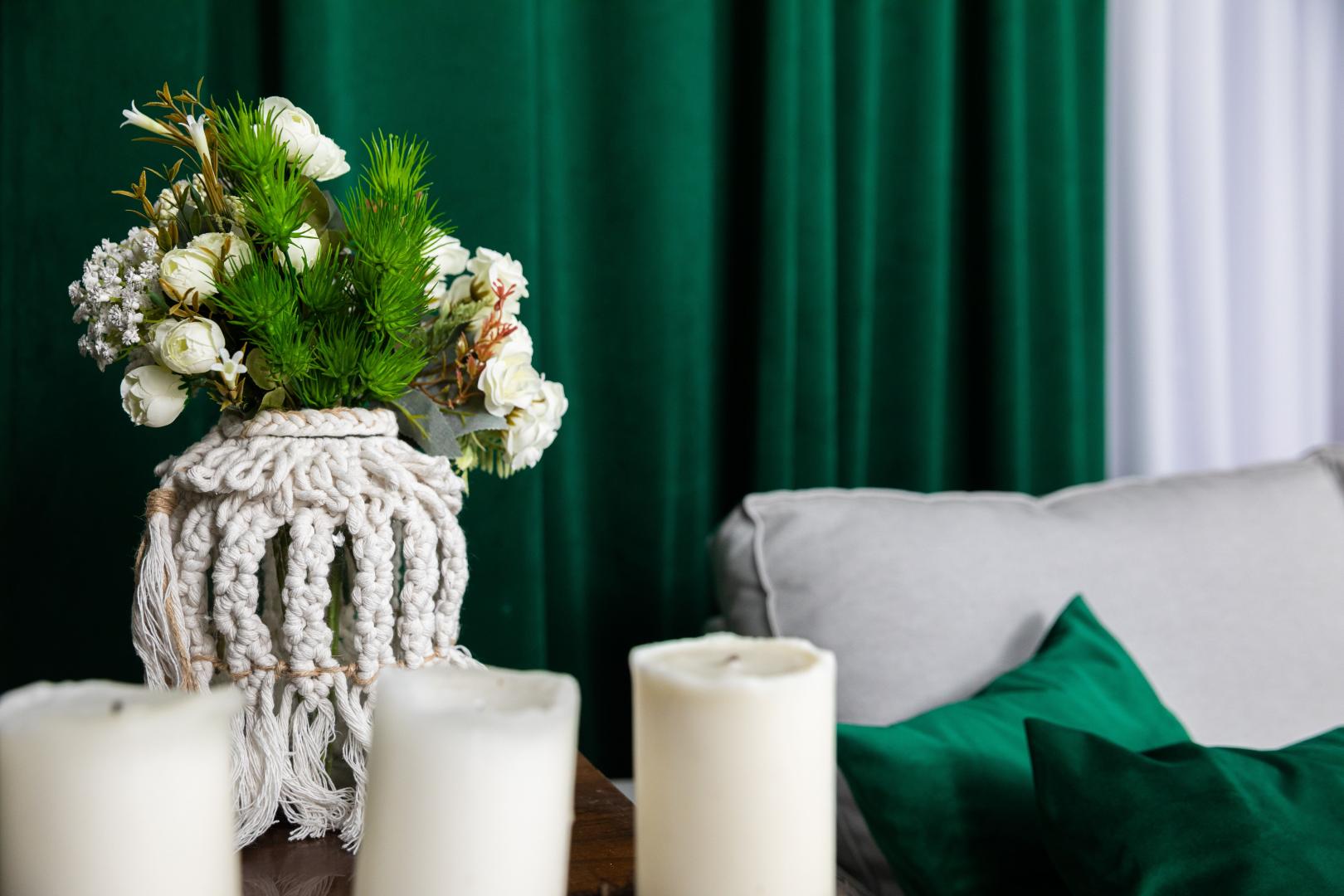 A corner of a room decorated with green pillows and green curtains.