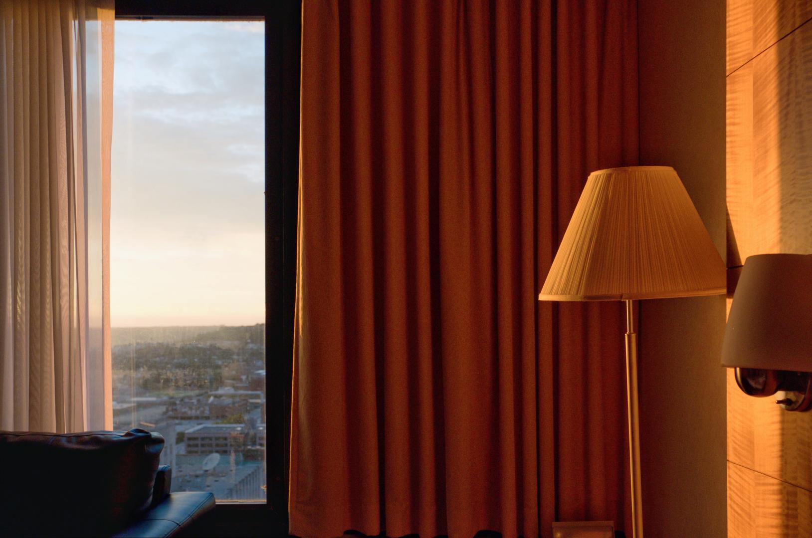 A window with sheer curtains and orange blackout curtains.