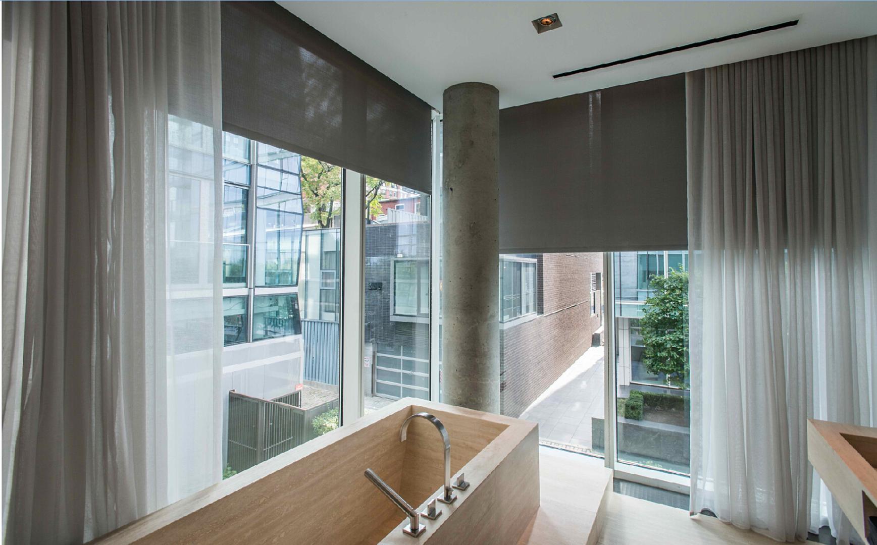 A corner with large glass windows, and a motorized curtain system.