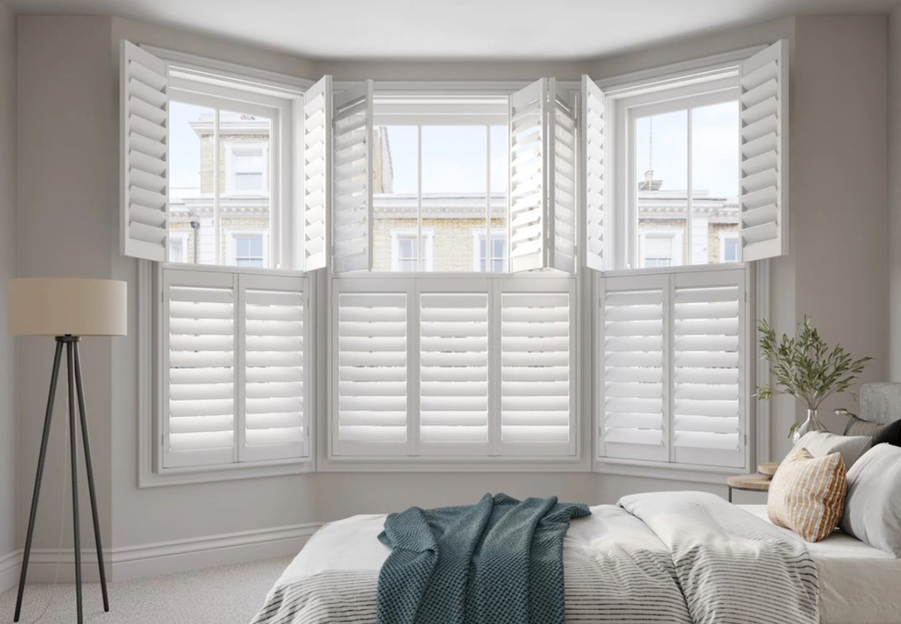 A white bedroom with large indoor window shutters.