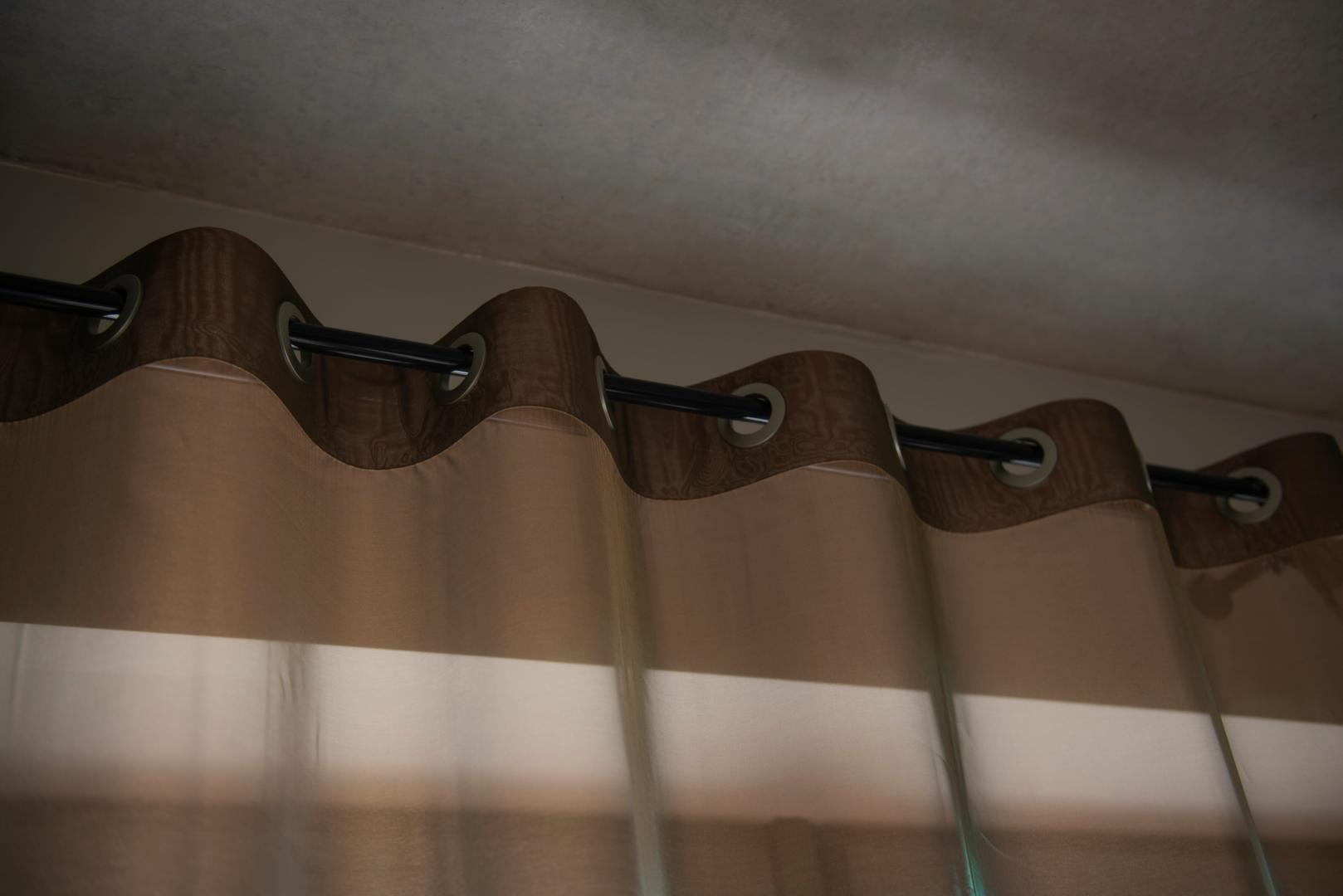 A close-up of brown grommet top drapes.