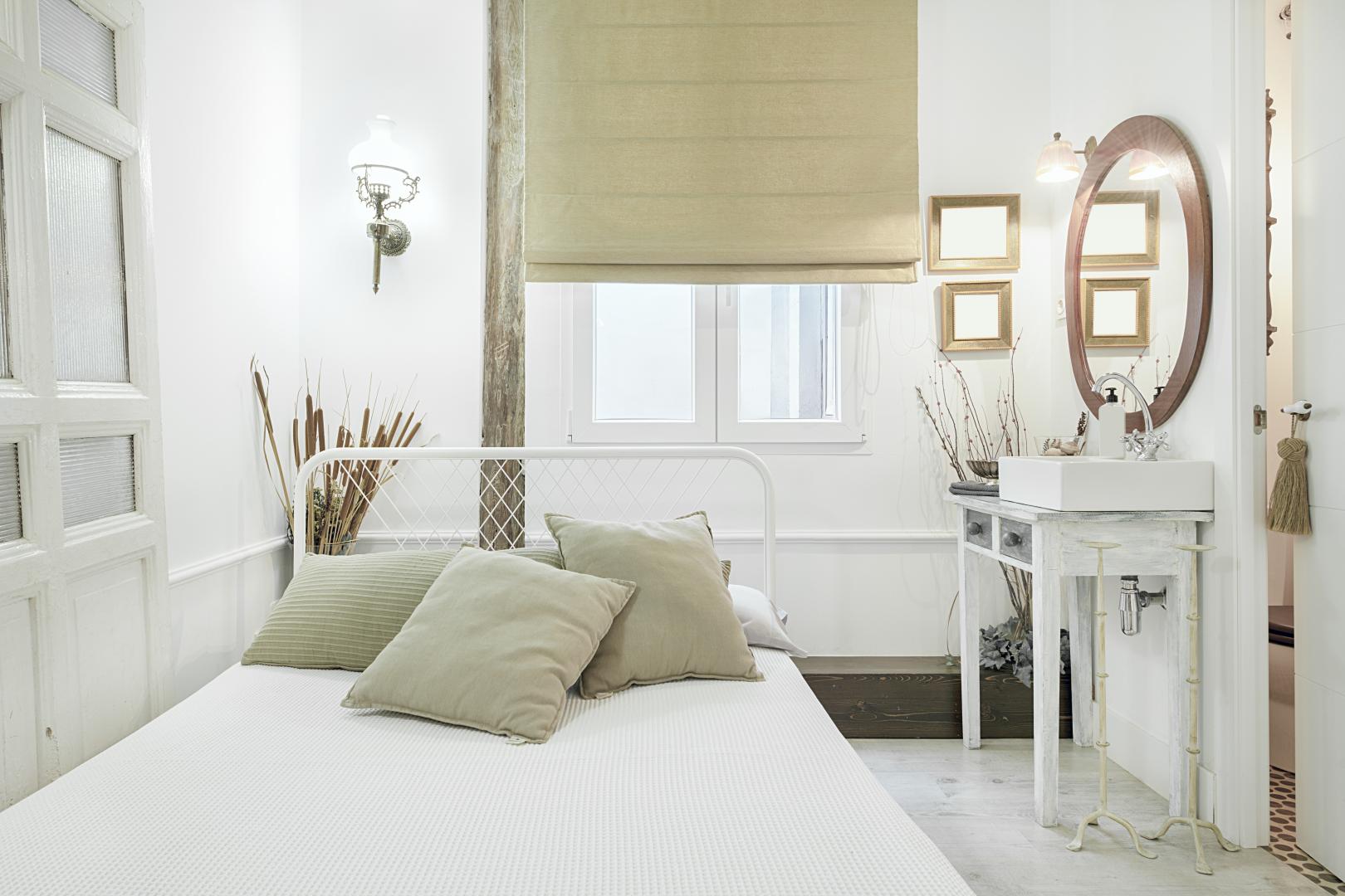 A bright, small bedroom with roller shades.