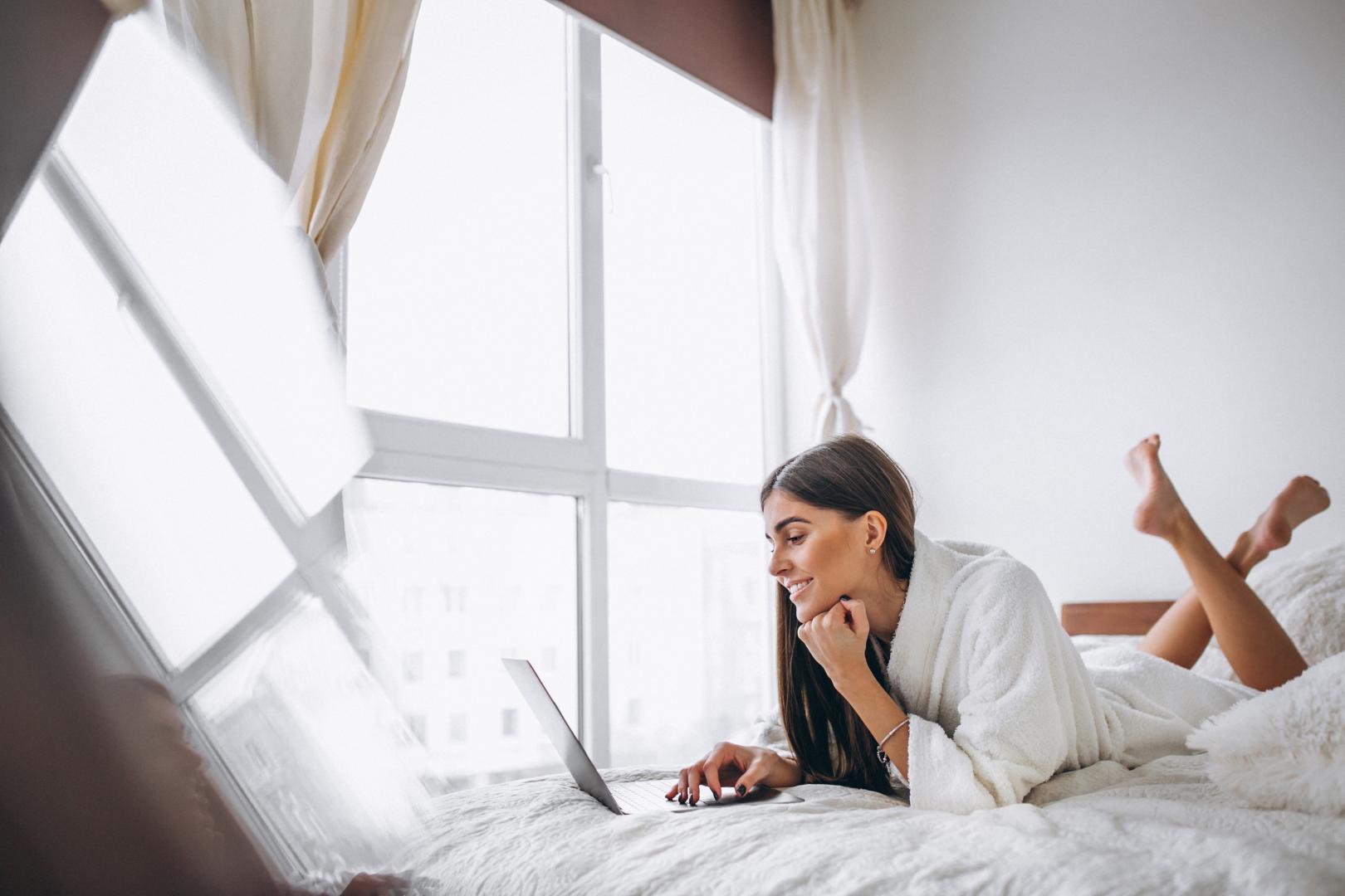 A woman in a bright bedroom with a large window.