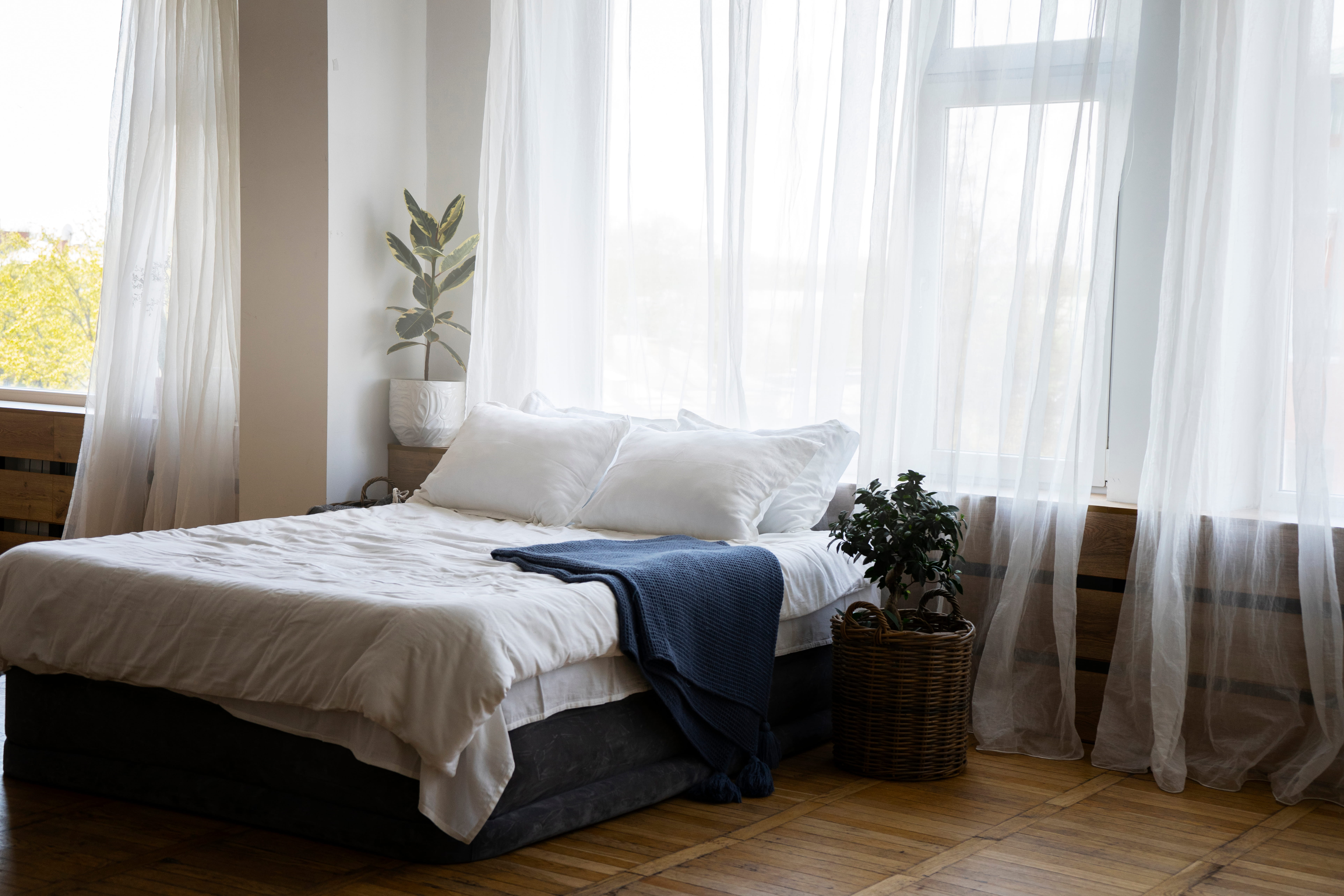 A bedroom with sheer white curtains.