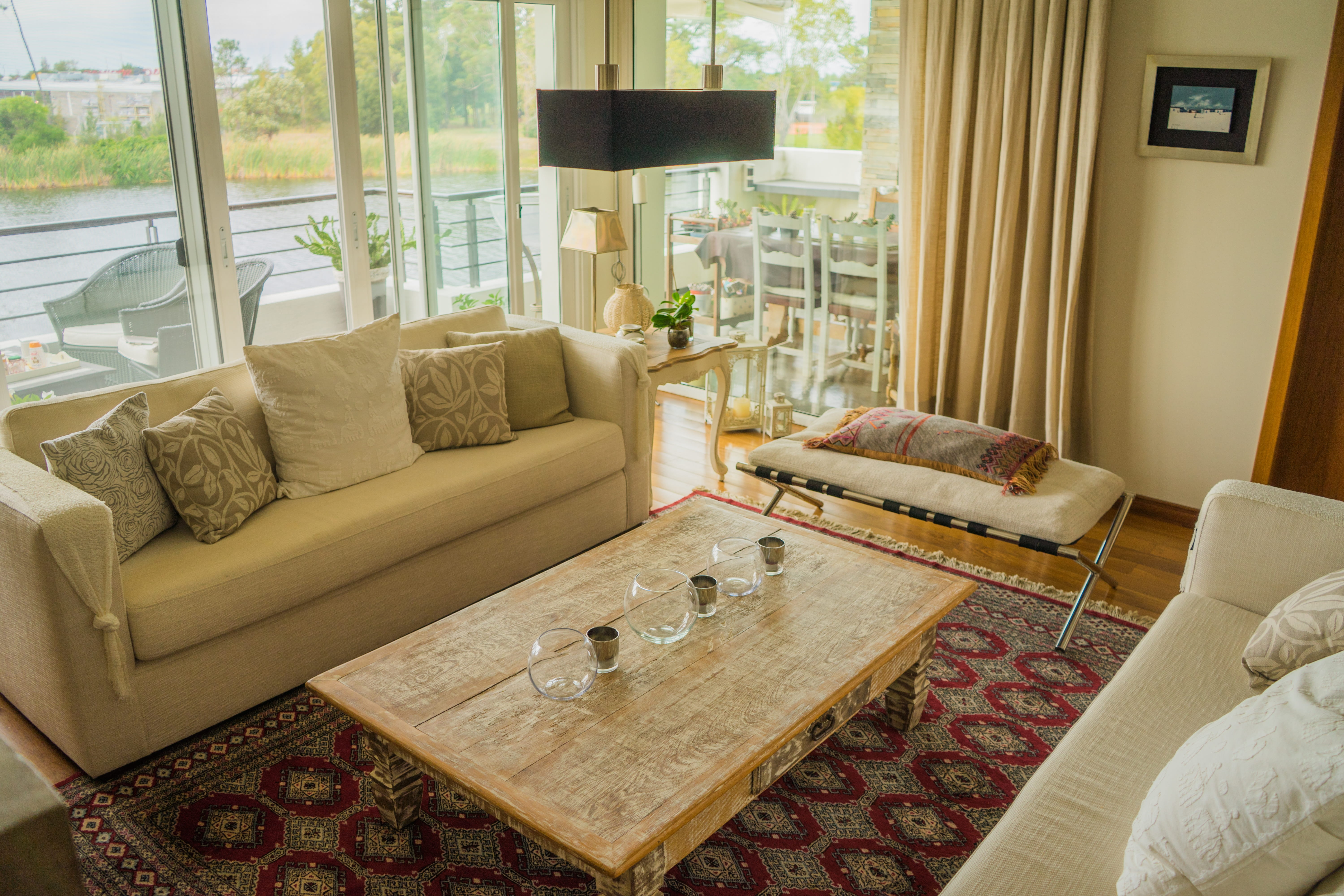 A modern, bright living room, with large windows, a balcony, and curtains.