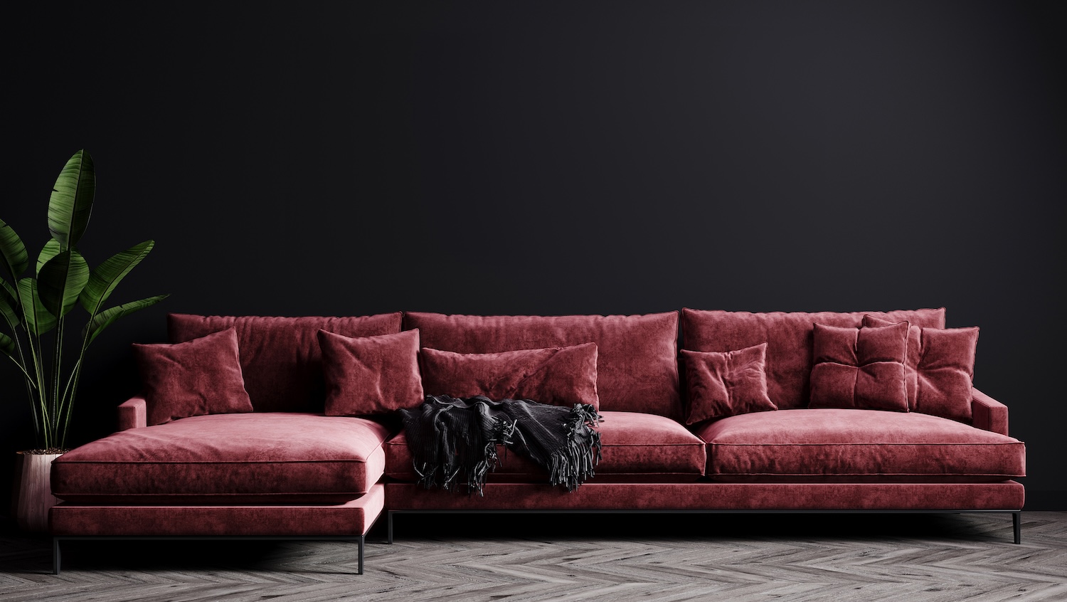 A luxurious red chenille couch against a black wall.