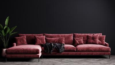 A luxurious red chenille couch against a black wall.