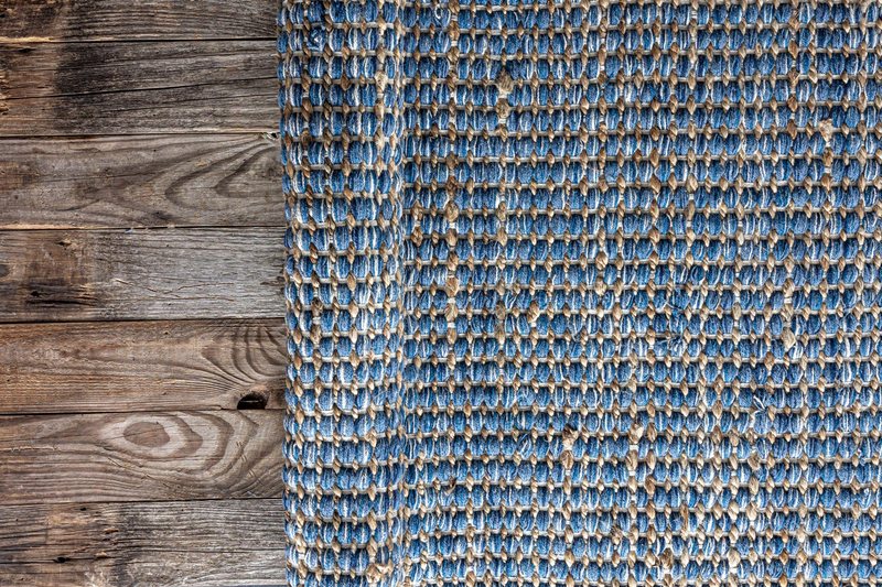 Hand woven geometric denim area rug on wooden floor