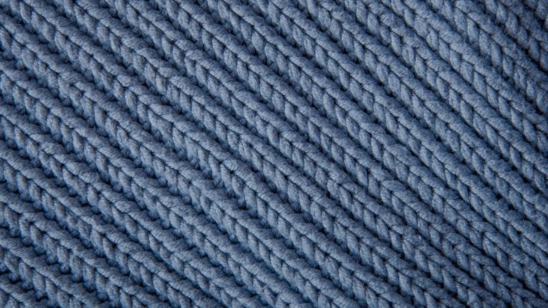 Close-up of a soft blue knit fabric, with an intricate texture and cozy appearance.