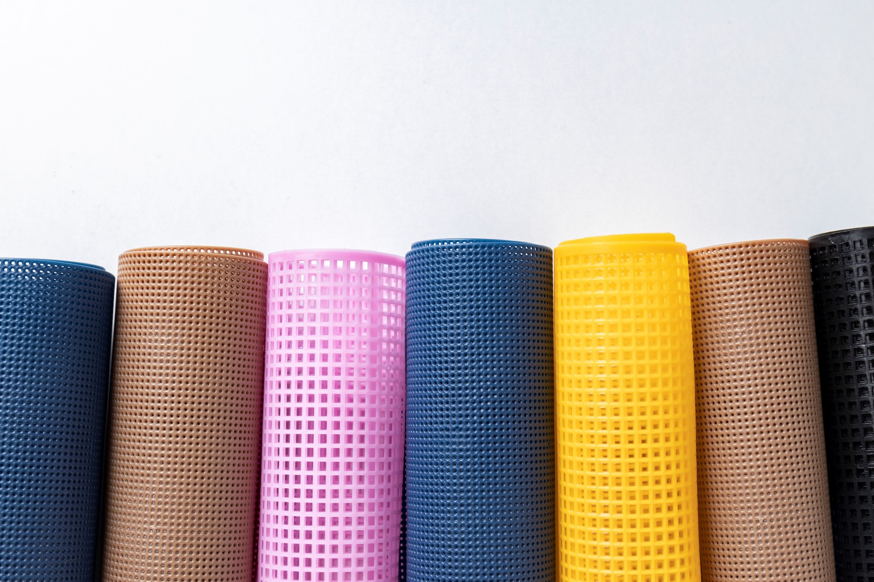 Bright and colorful rolls of synthetic mesh rolls against a white background.