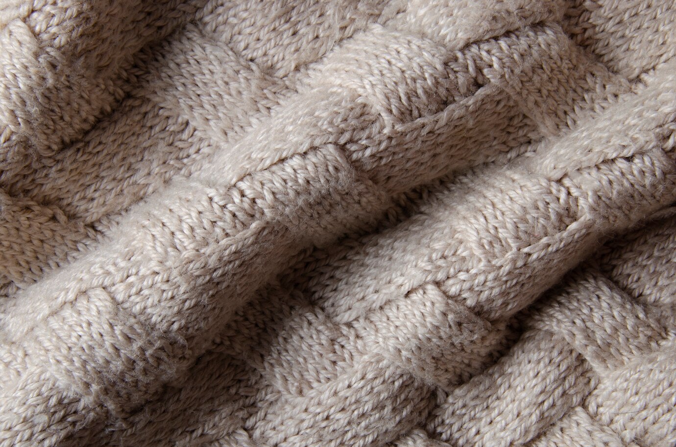 Close-up of a beige wool knitted blanket showcasing an intricate pattern.