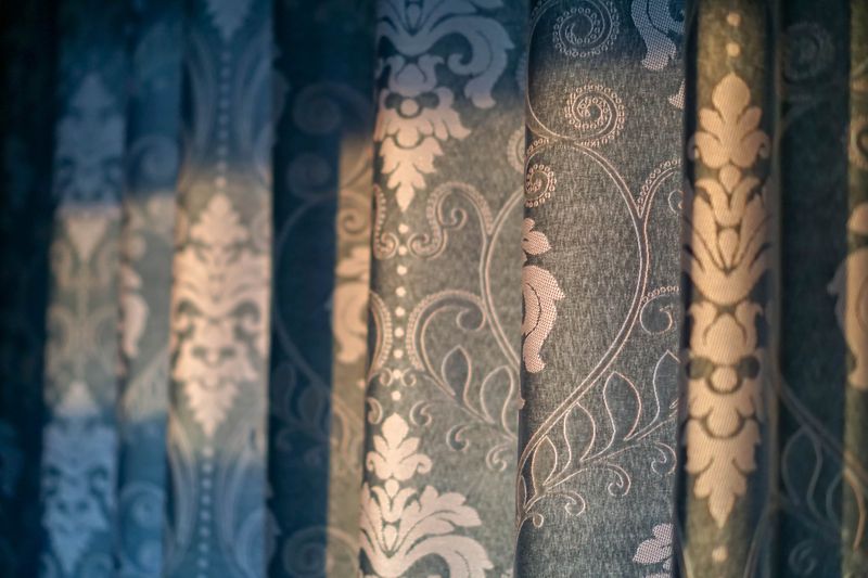 Close-up of ornate patterned curtains, featuring intricate designs in shades of blue and beige.