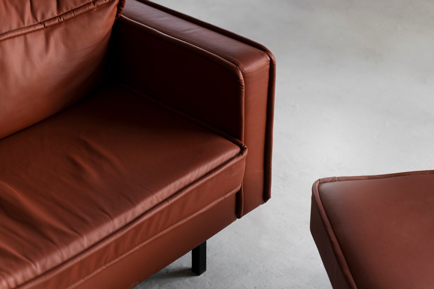A close-up view of a luxurious brown leather couch and matching ottoman.