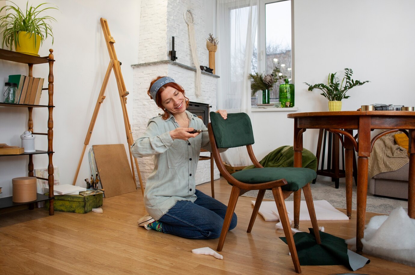 A woman sitting on the floor next to a chair, attaching a new green seat to it.
