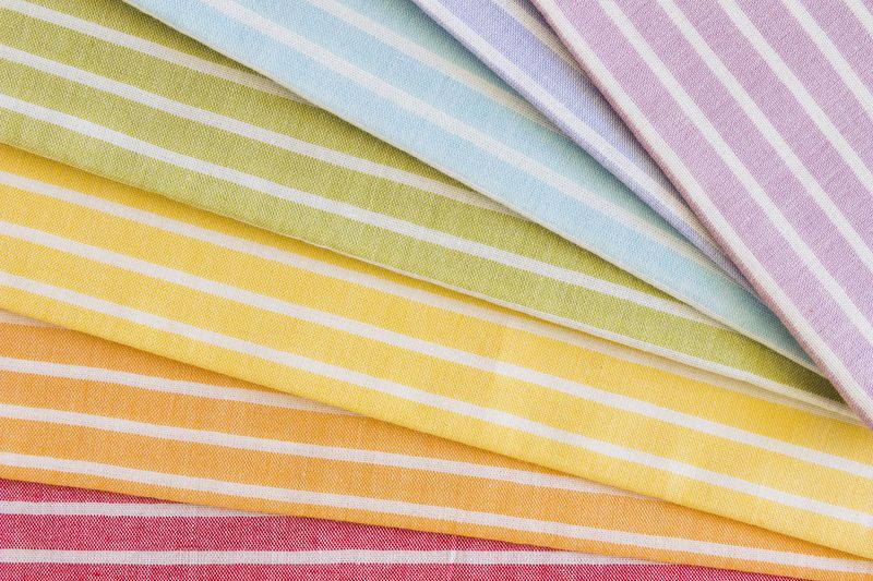An assortment of colorful striped fabric arranged in a rainbow pattern, in a variety of colors.