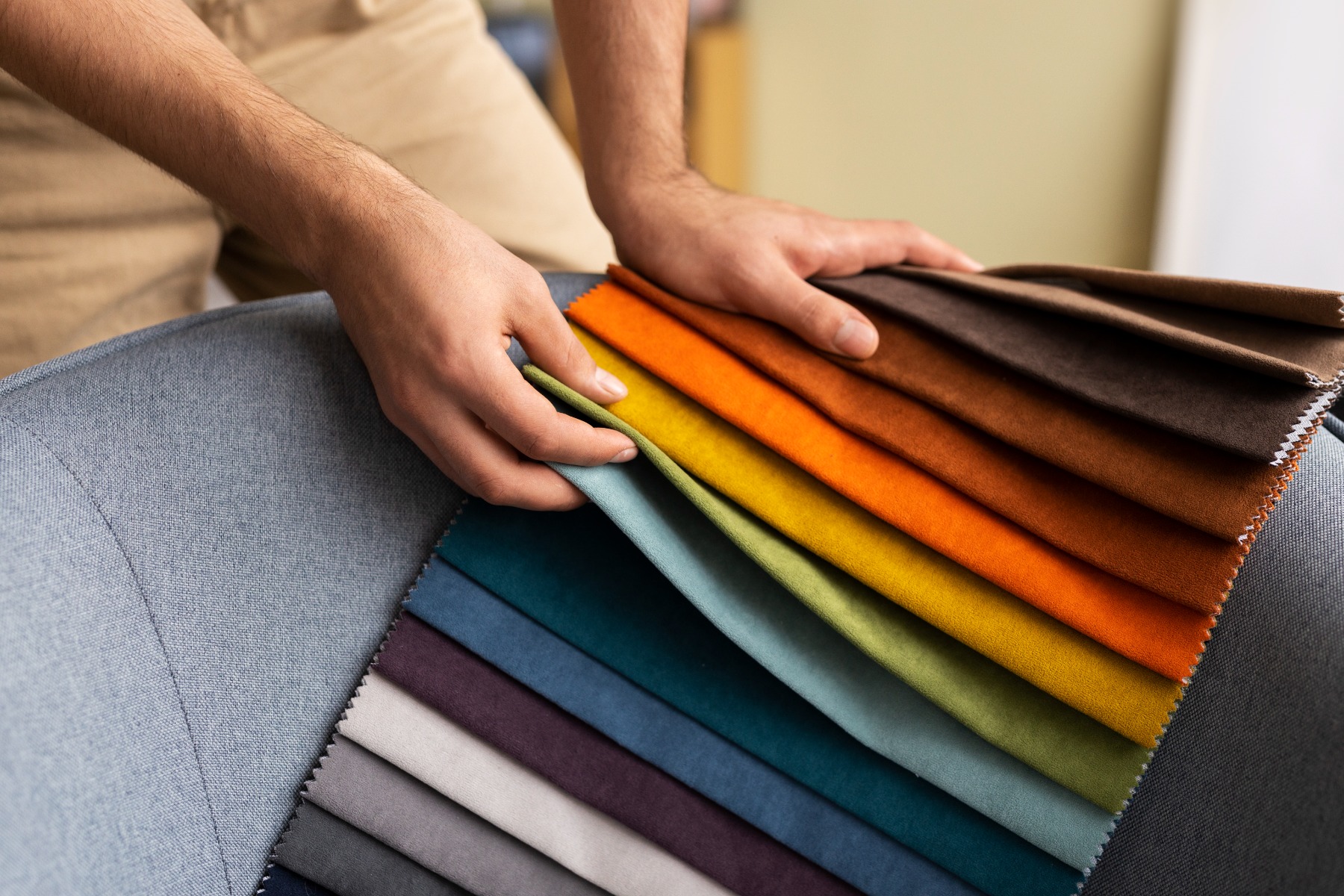 A man's hands going through a bunch of fabric samples in many different colors.