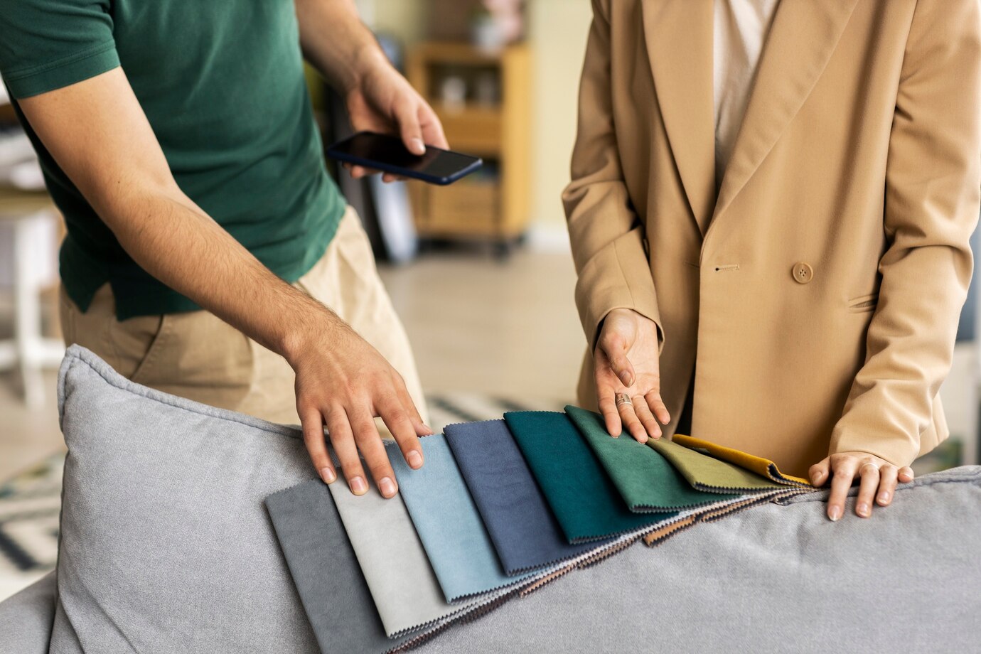 A man and a woman reviewing a selection of sofa fabrics in different colors.