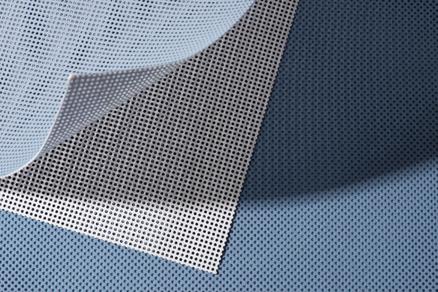 A smooth non-woven fabric sheet against a bright blue background.