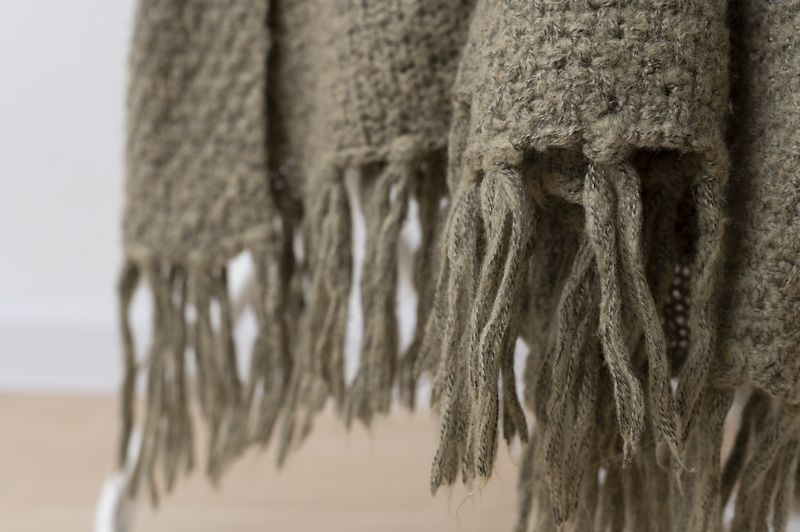 A close-up view of a cozy wool blanket featuring soft fringes along the edges, adding texture and warmth.
